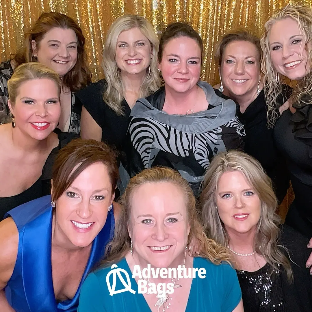 Group of guests smiling in front of a gold sequin backdrop at a gala