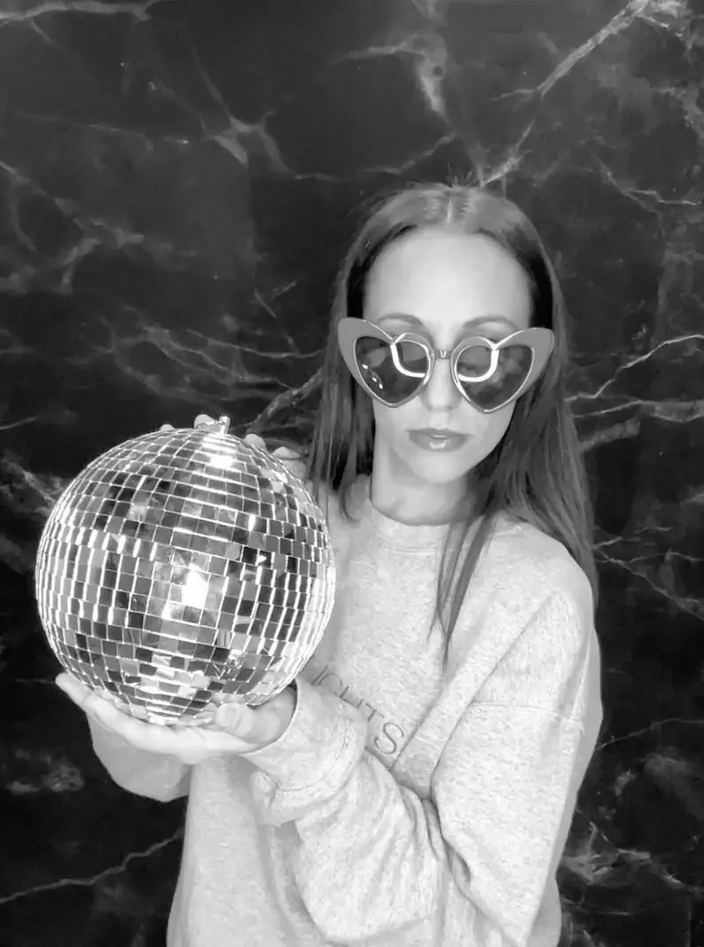 Guest holding a disco ball in a black and white photo booth portrait
