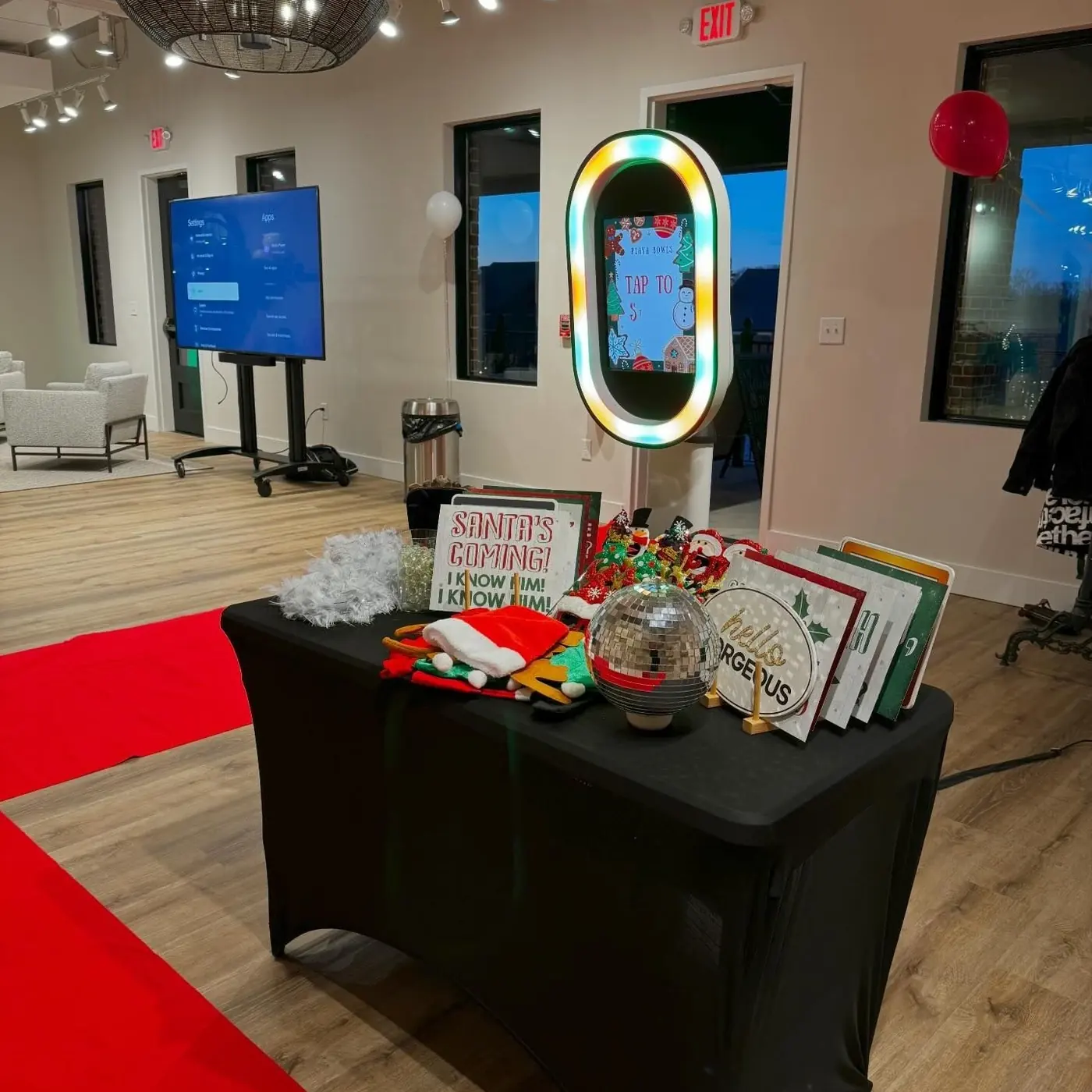 Photo booth setup with prop table and red carpet at a holiday event
